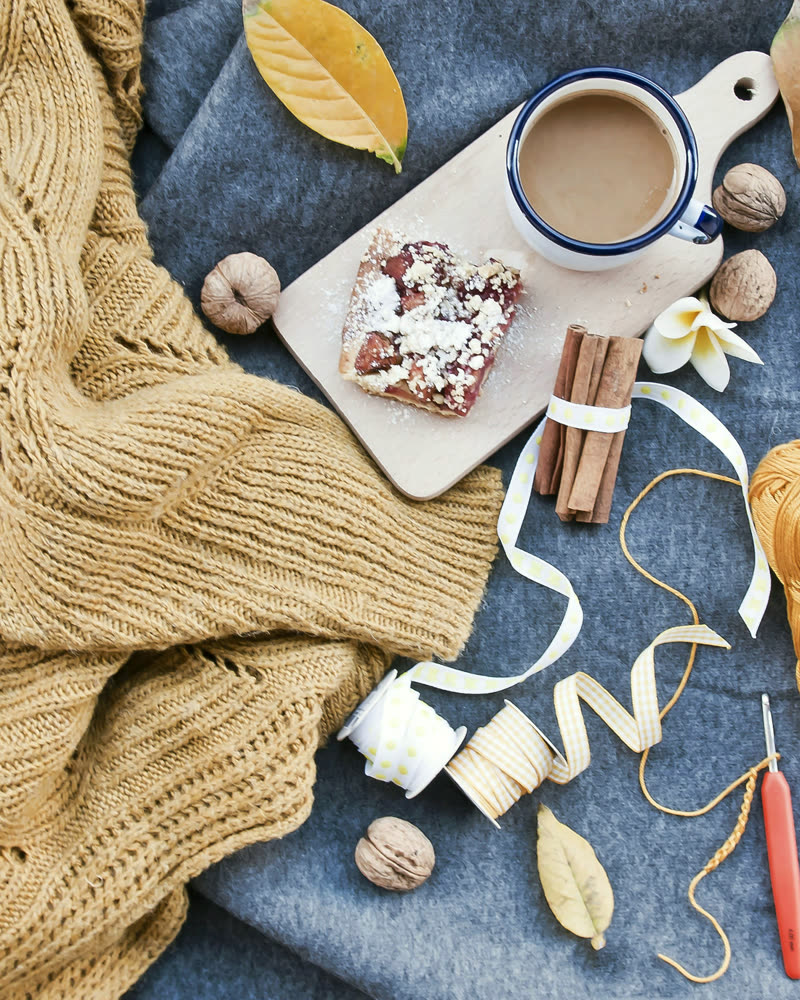 Coffee, a knitted throw and pastries on a blue linen table